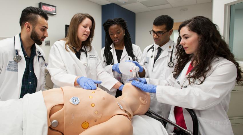 A group of residents practicing a CPR on a dummy during a training class.