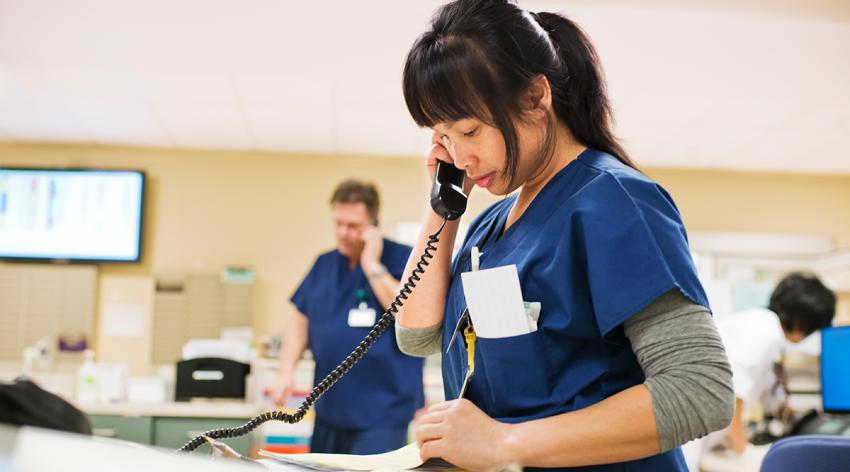 Nurse checks notes while talking on phone