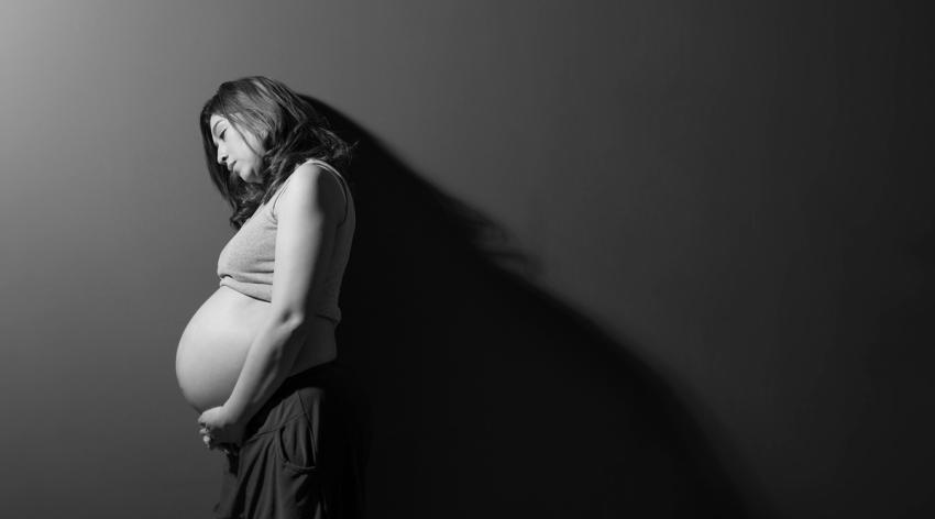 Pregnant woman leaning against a wall