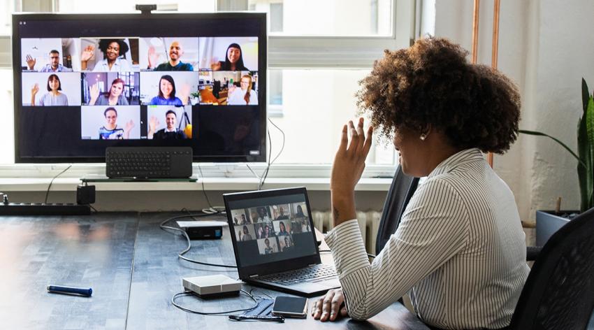 Rear view of a businesswoman having a meeting with team over a video conference in office board room.