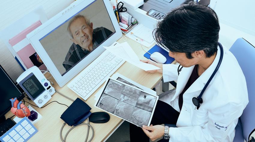 Doctor looking at coronary x-ray output while on a video call with a patient