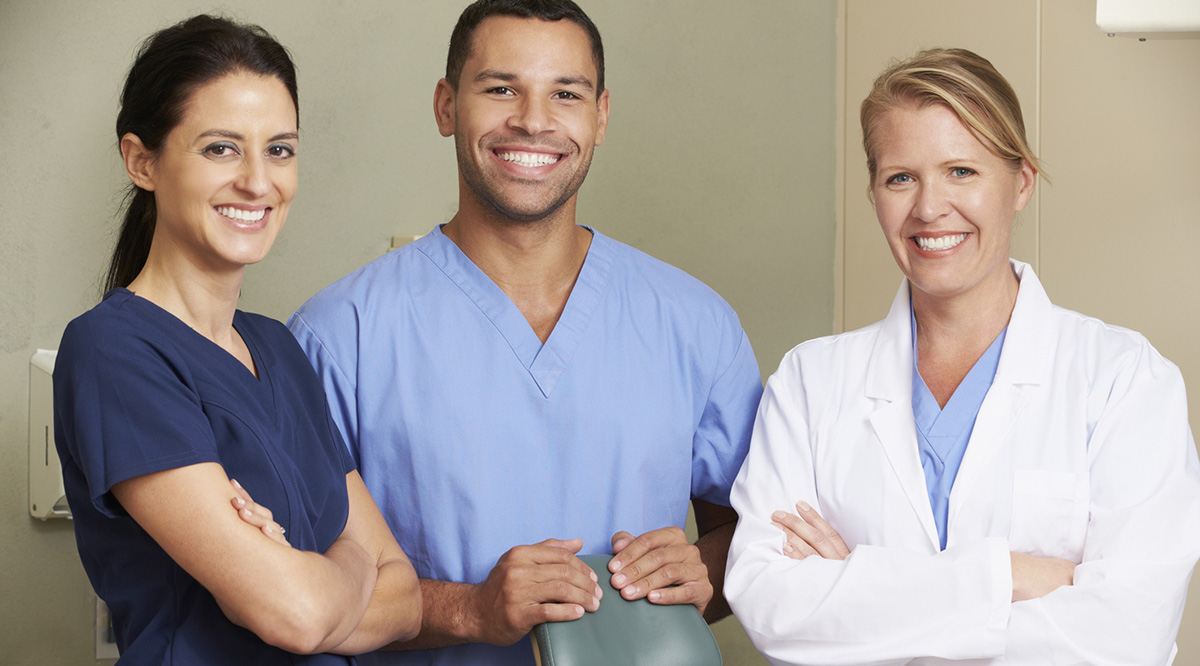 Three health professionals look toward the camera and smile. 