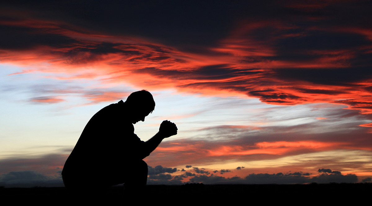 Fotografia do Stock: Man pray with arms stretched out to a sunset