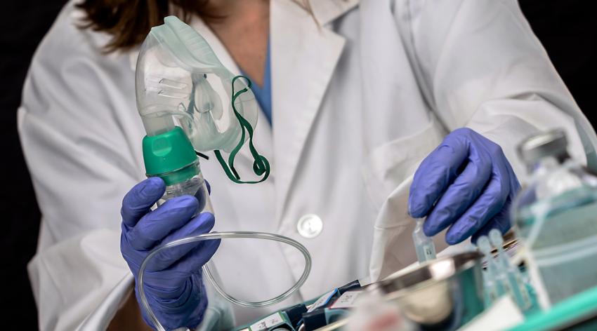A female medical staff holding an oxygen mask inside a hospital.