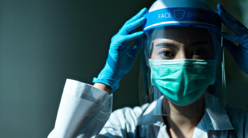 A doctor wearing a face shield and wearing a mask and gloves