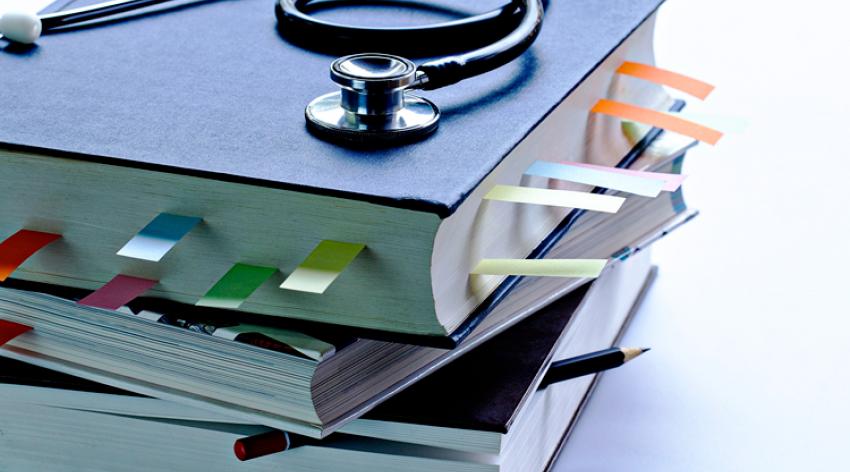 Medical student textbooks with pencil and multicolor bookmarks and stethoscope.