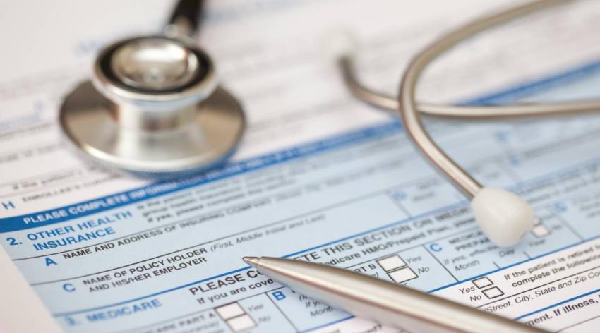 A stethoscope on top of a health insurance form