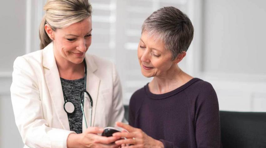 A physician looking at a mobile device with a patient