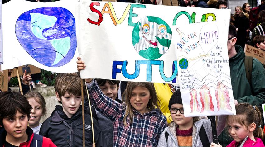 Children at a climate change protest holding signs that say “save our future”