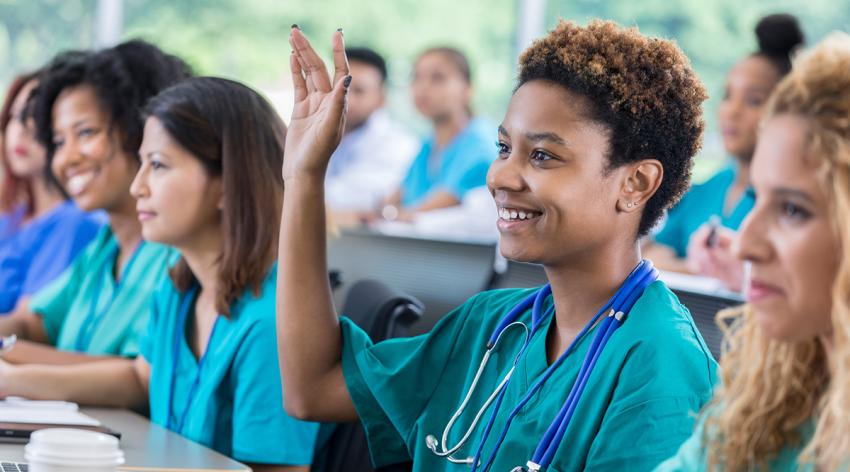Smiling African American nursing student raises hand during class